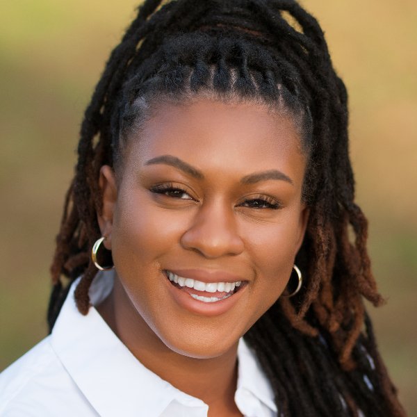 Dana Young-Askew - Black woman with long hair, smiling big at camera