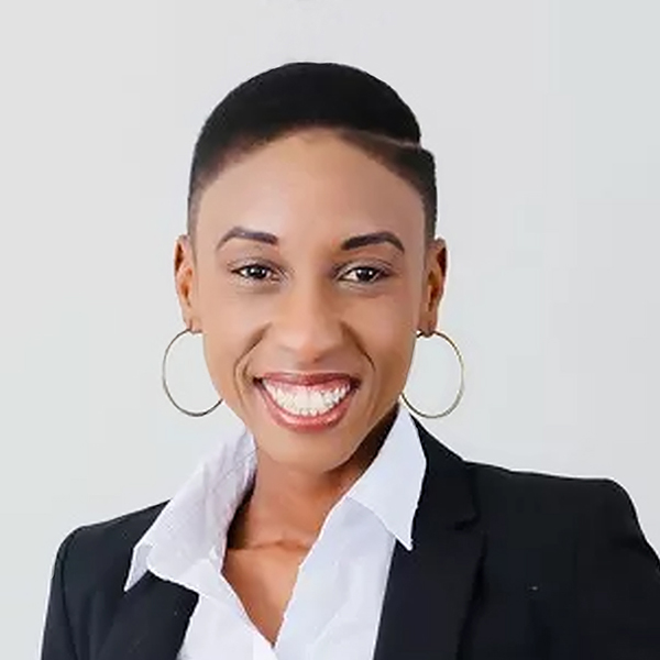 Headshot of Annette Serwanga - a Black woman with short black hair, gold hoop earrings, white collared shirt, smiling big