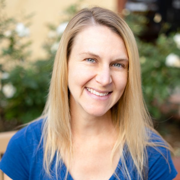 Headshot for Jamie Chaves - a white woman with long straight blond hair, blue eyes, wearing a blue v-neck top, smiling