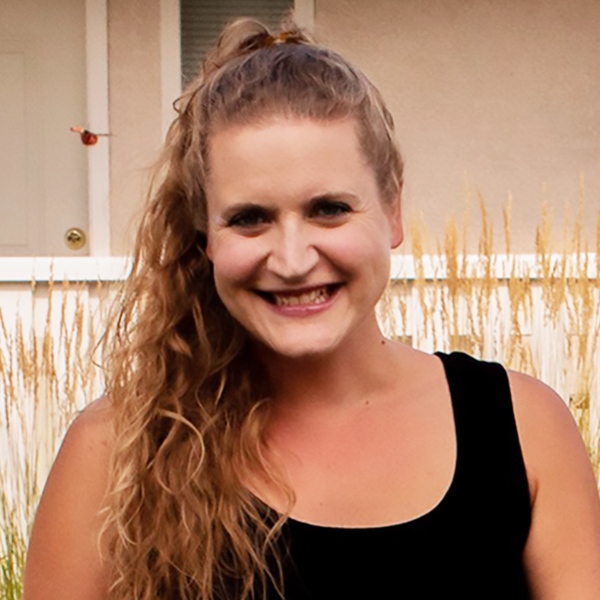 Headshot for Laranna - light skinned Metis woman with long blonde hair in a ponytail, smiling in a black top