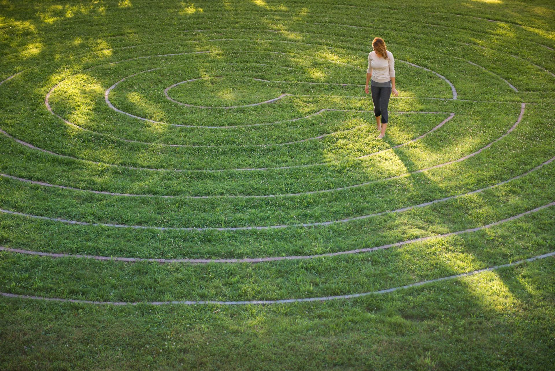 woman walking a large grass labyrinth