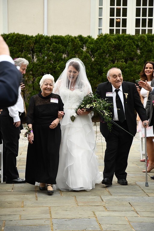 Bride walking down the aisle with her grandparents, bubbie and zaide. All are laughing and joyful.