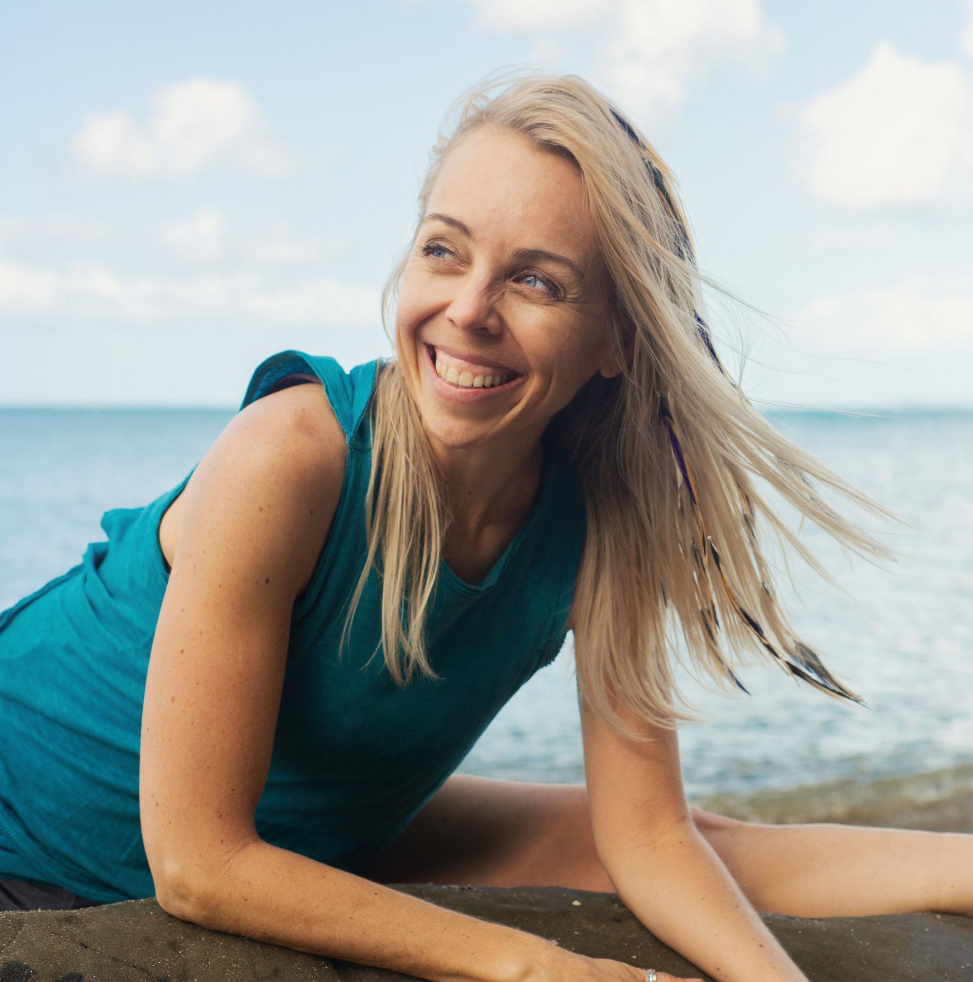 Pilates instructor Kim West stretching on a New Zealand beach.