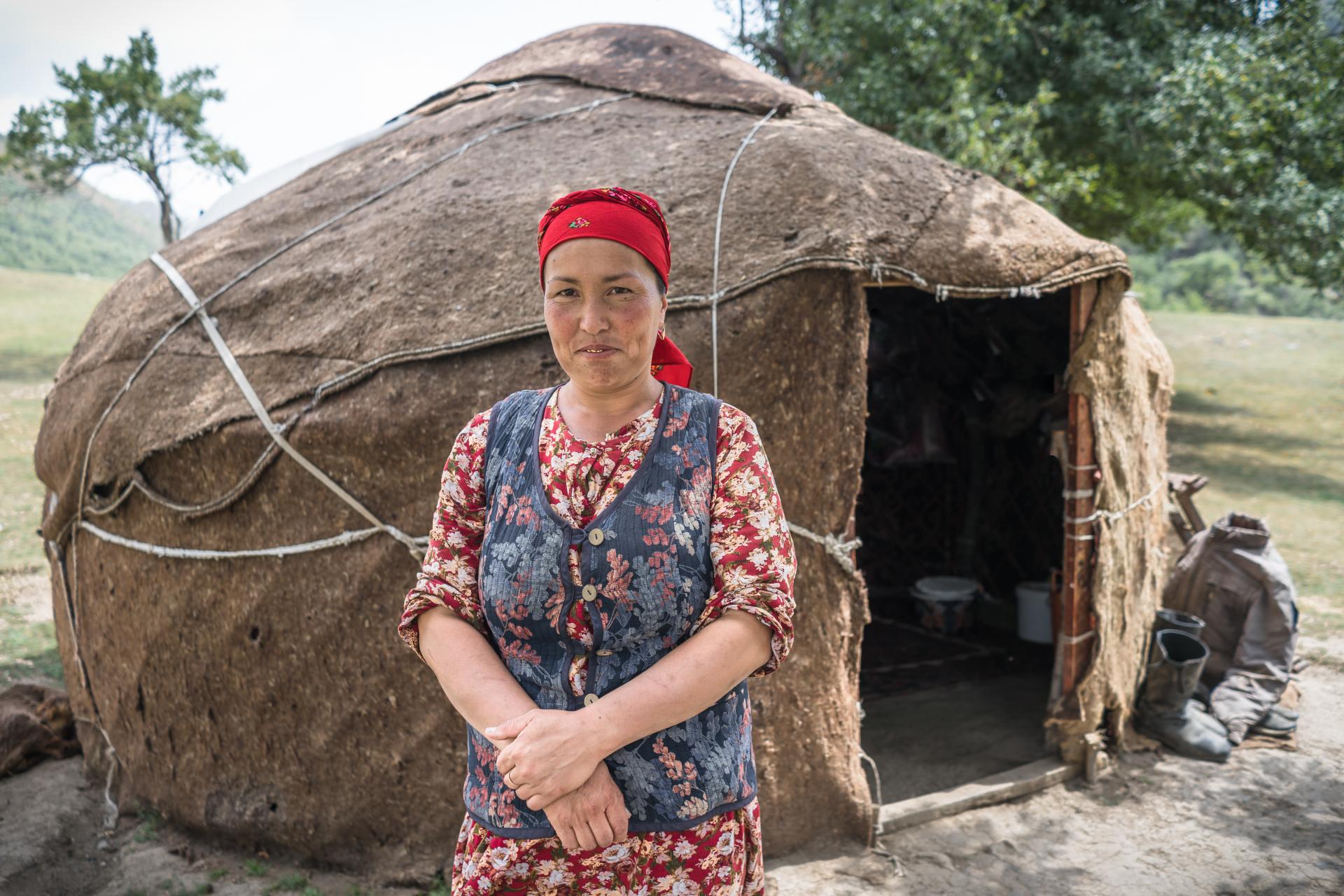 Kyrgyz woman standing outside traditional yurt dwelling - Central Asia cultural experience with Raw Tours