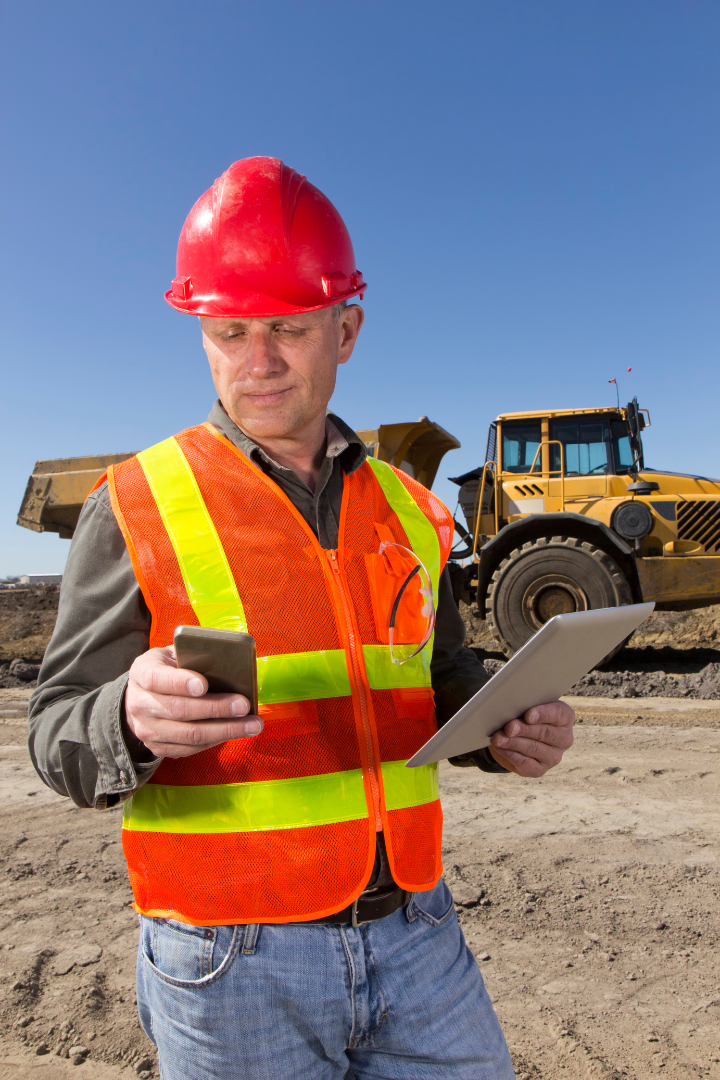 Construction team leader holding a clipboard and cellphone in a construction site