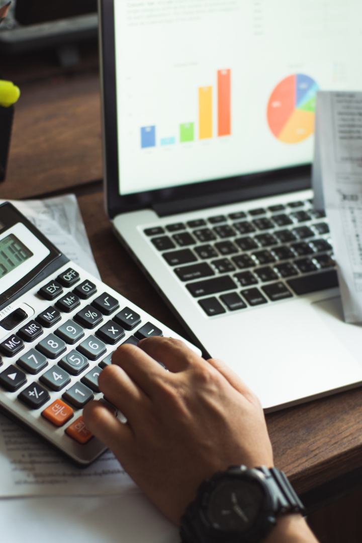 Man entering values on a calculator and laptop with graph