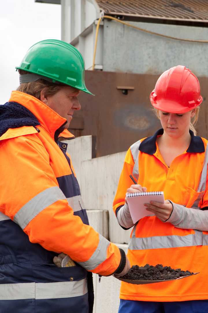 Trainee writing in paper learning from an experienced construction worker