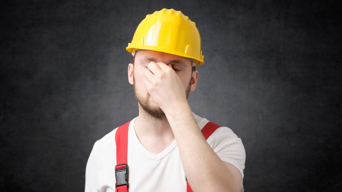 Stressed construction worker covering face with hands
