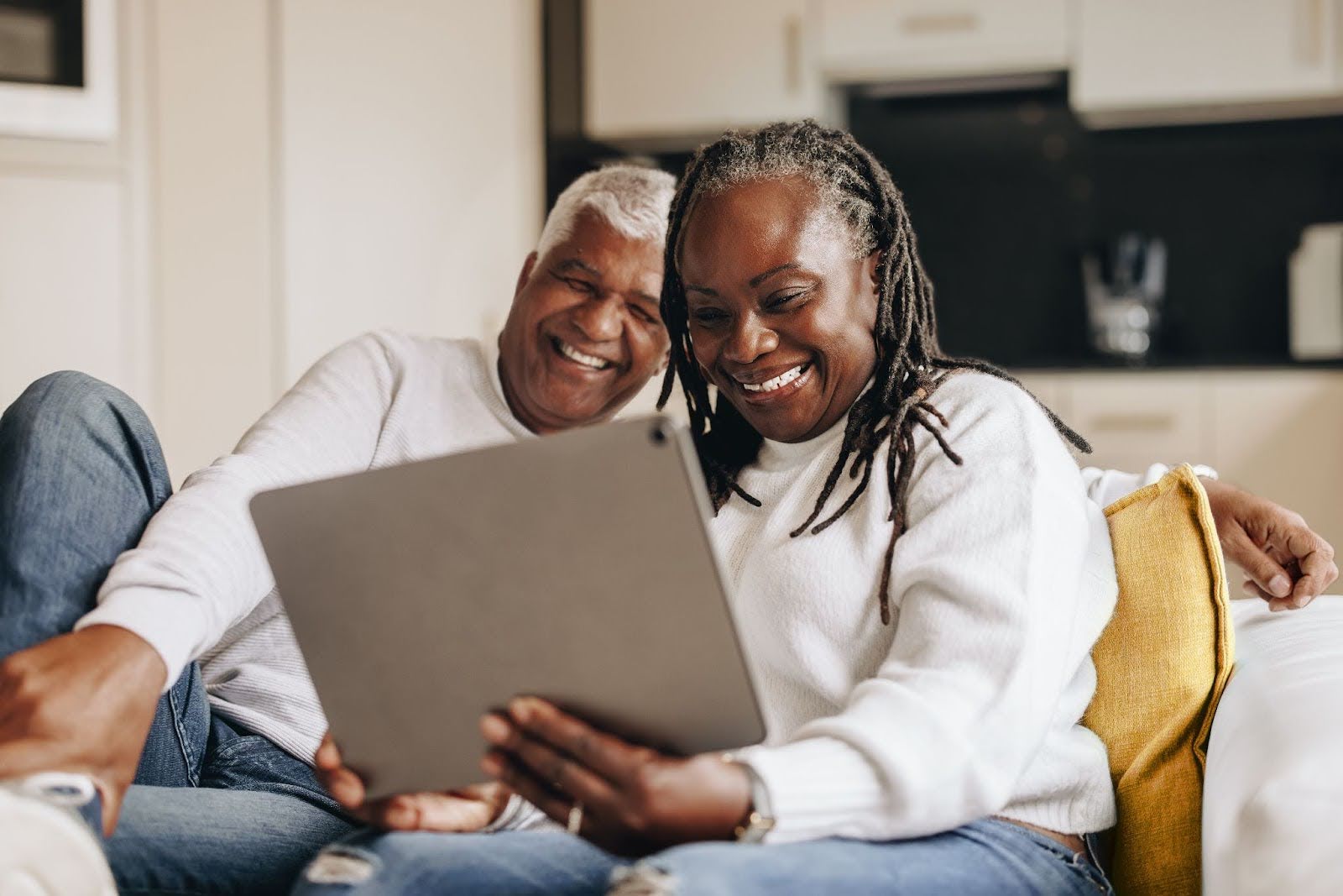 Happy senior couple sitting on a couch with an iPad 