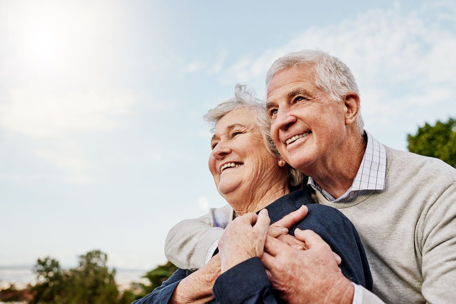 a senior couple hugging and smiling 