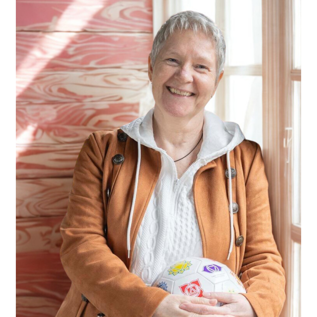 Karen Peters smiling, leaning against a window and holding the Cognomovement ball