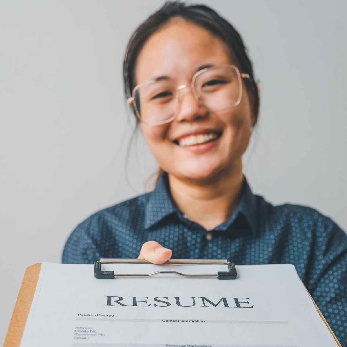 Woman reaching forward, handing over her resume for review.