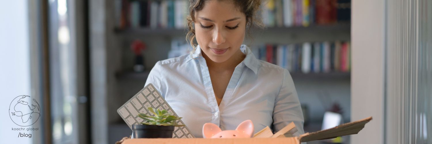 Woman leaving her office, carrying a box of her belongings.