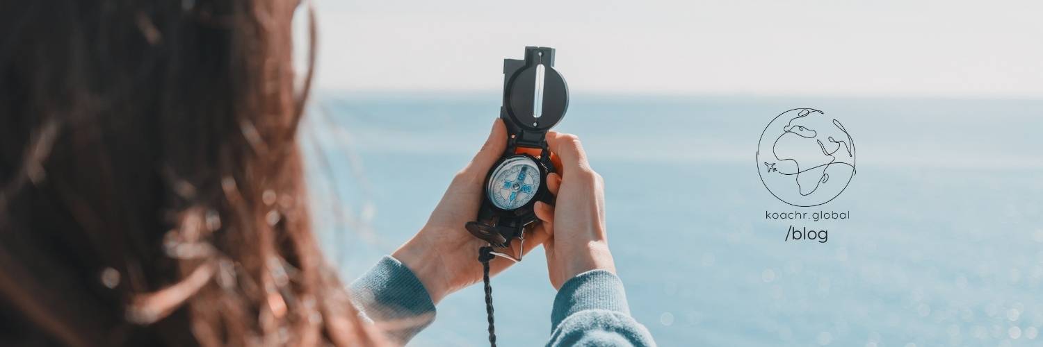 Woman holding a compass, overlooking the ocean, symbolizing career reflection and setting a direction