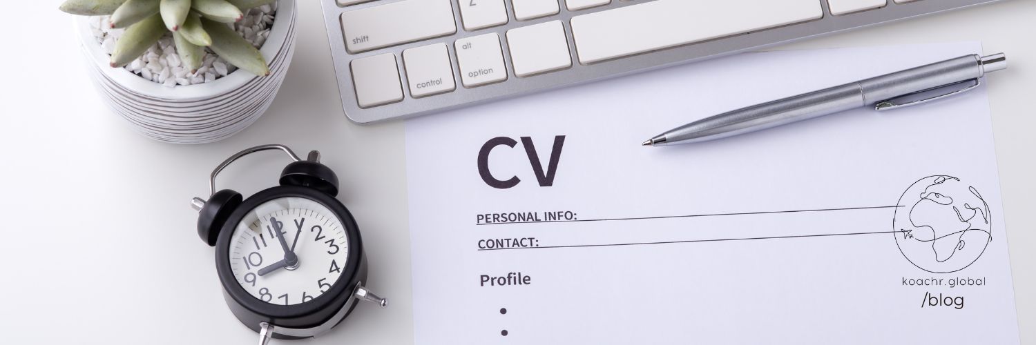 Details of a desk with a clock and a CV, a plant, a pen and a keyboard - for quick CV update!