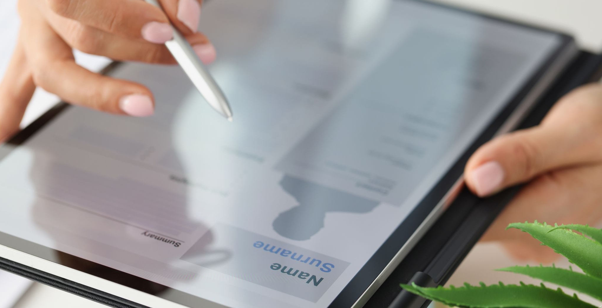 Close-up of an ipad displaying an application and a woman's hands working on it.