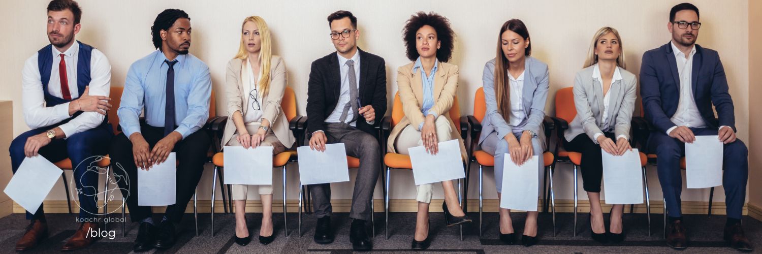 Group of professionals sitting along a wall, looking displeased.