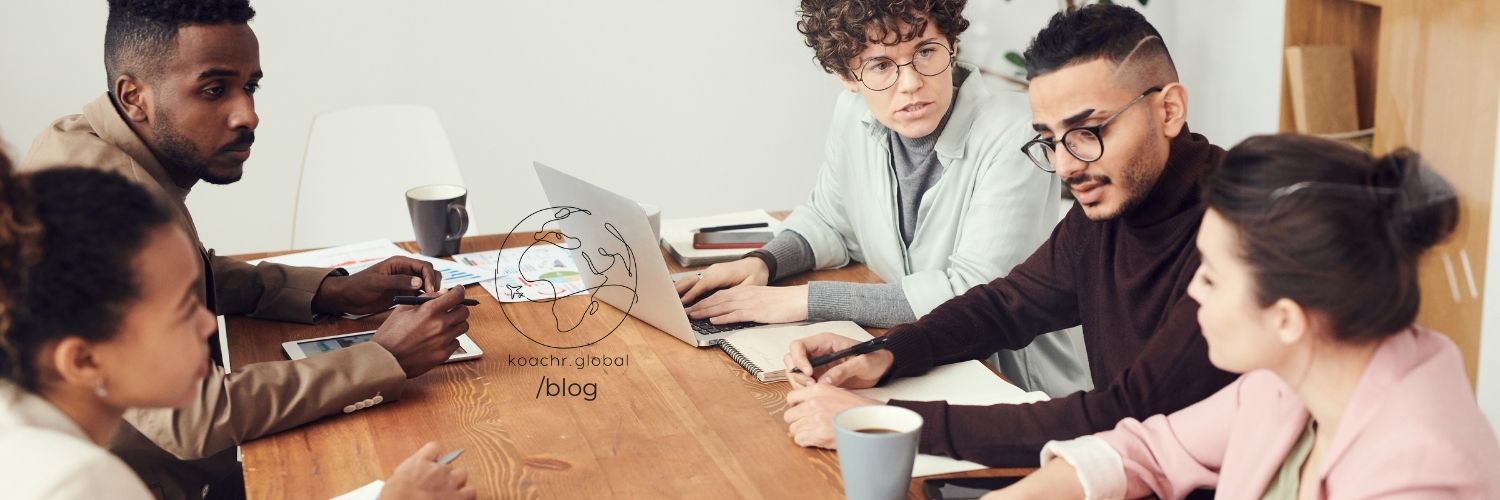 International civil servants from various cultural backgrounds, working together around a table with laptops and coffee cups