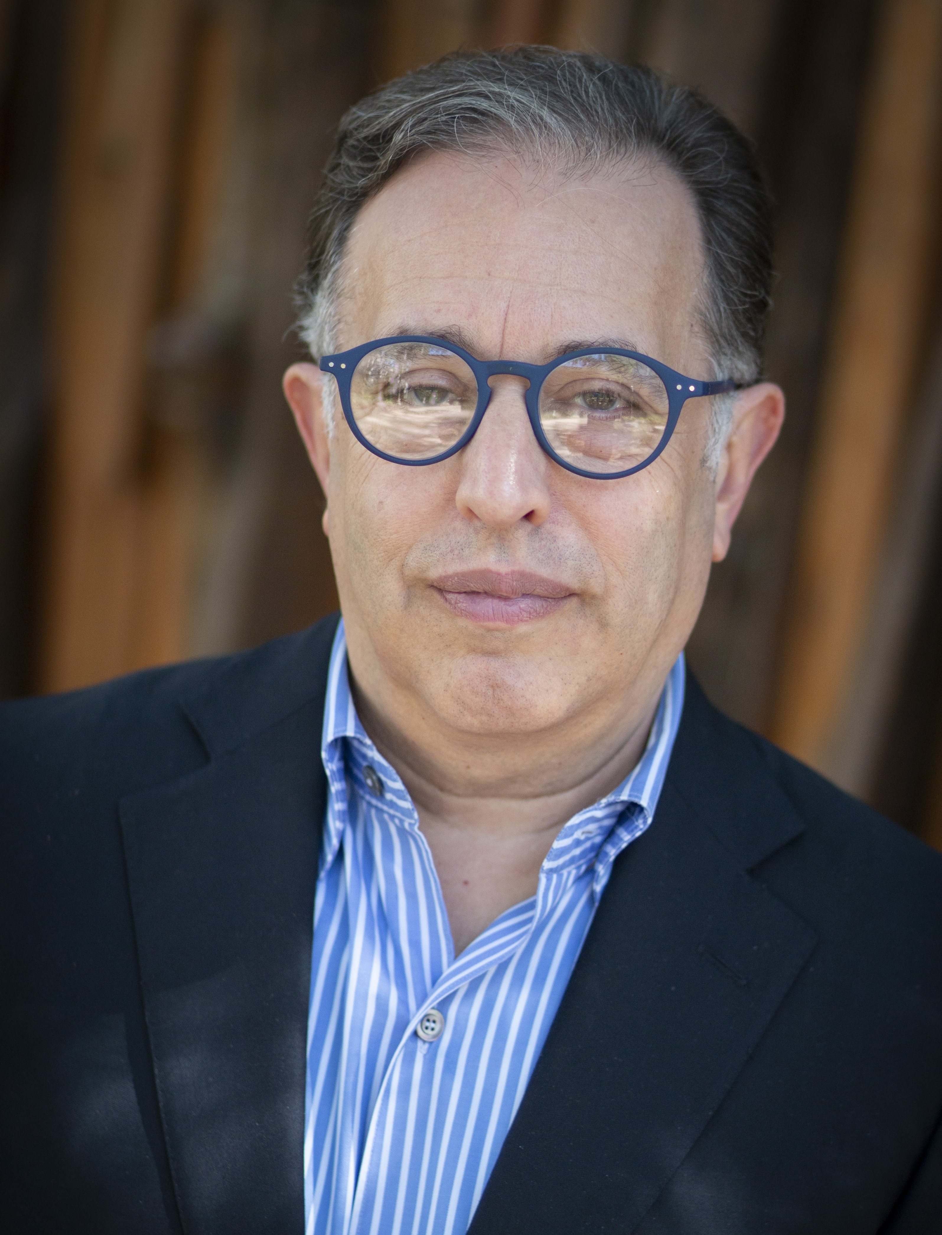 Rhodes Perry headshot - white man with a big smile, arms crossed, glasses, short beard, bald