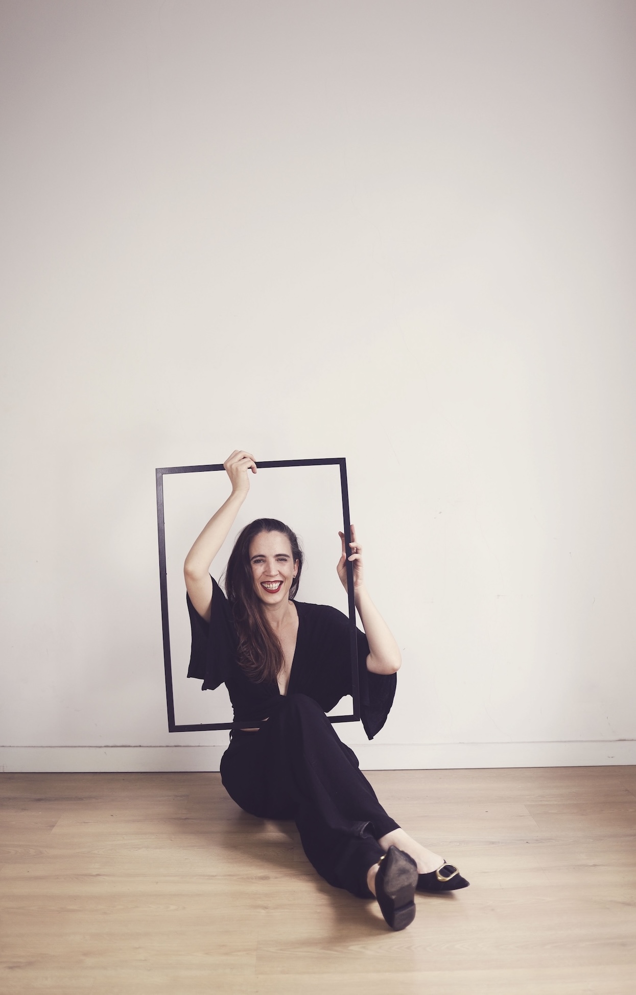 Blanca de la Cruz sentada en el suelo con un marco negro en sesión fotográfica artística