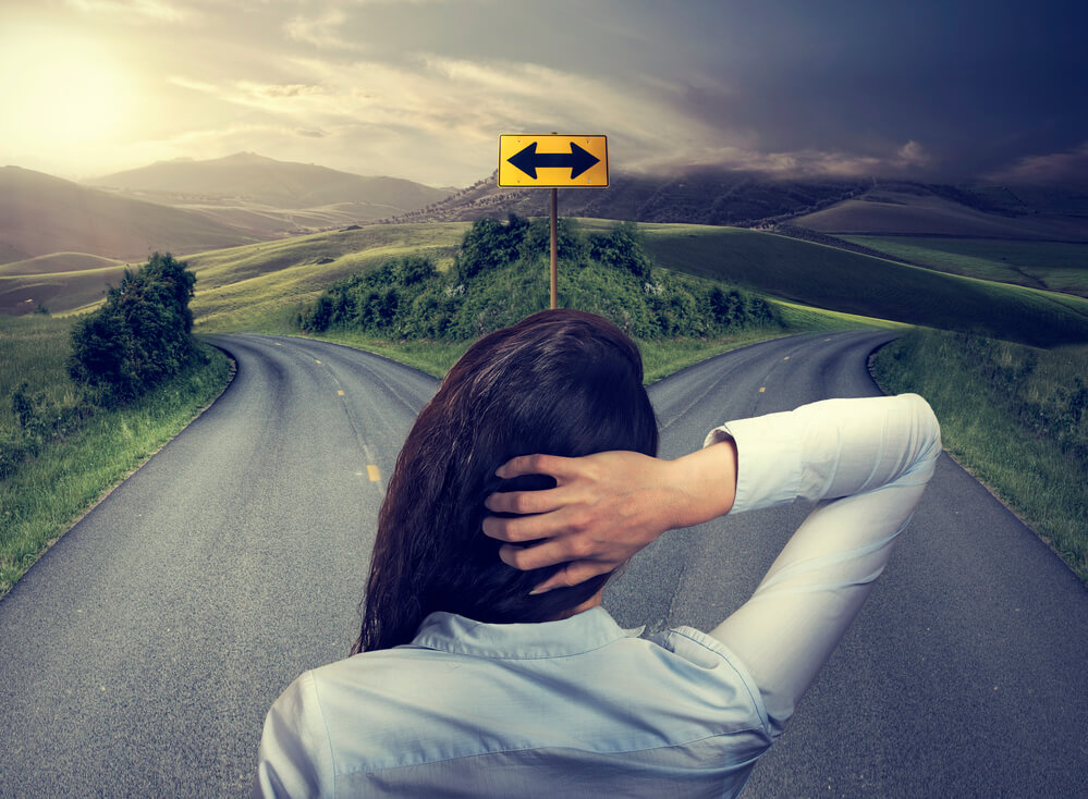 Woman stood at the fork in a road deciding which way to go