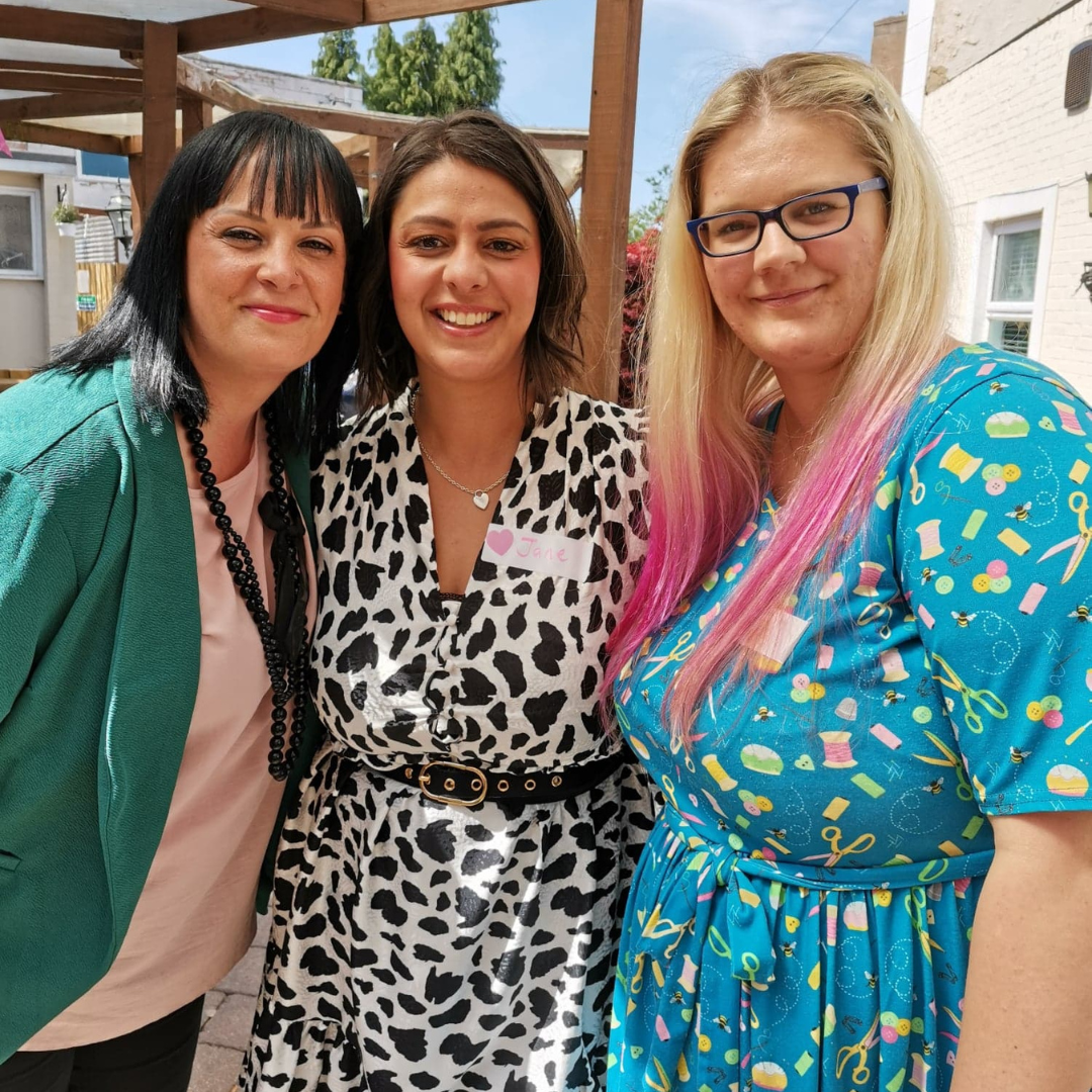 Dani, female business coach and mentor with blonde hair with pink ends, holding a coffee