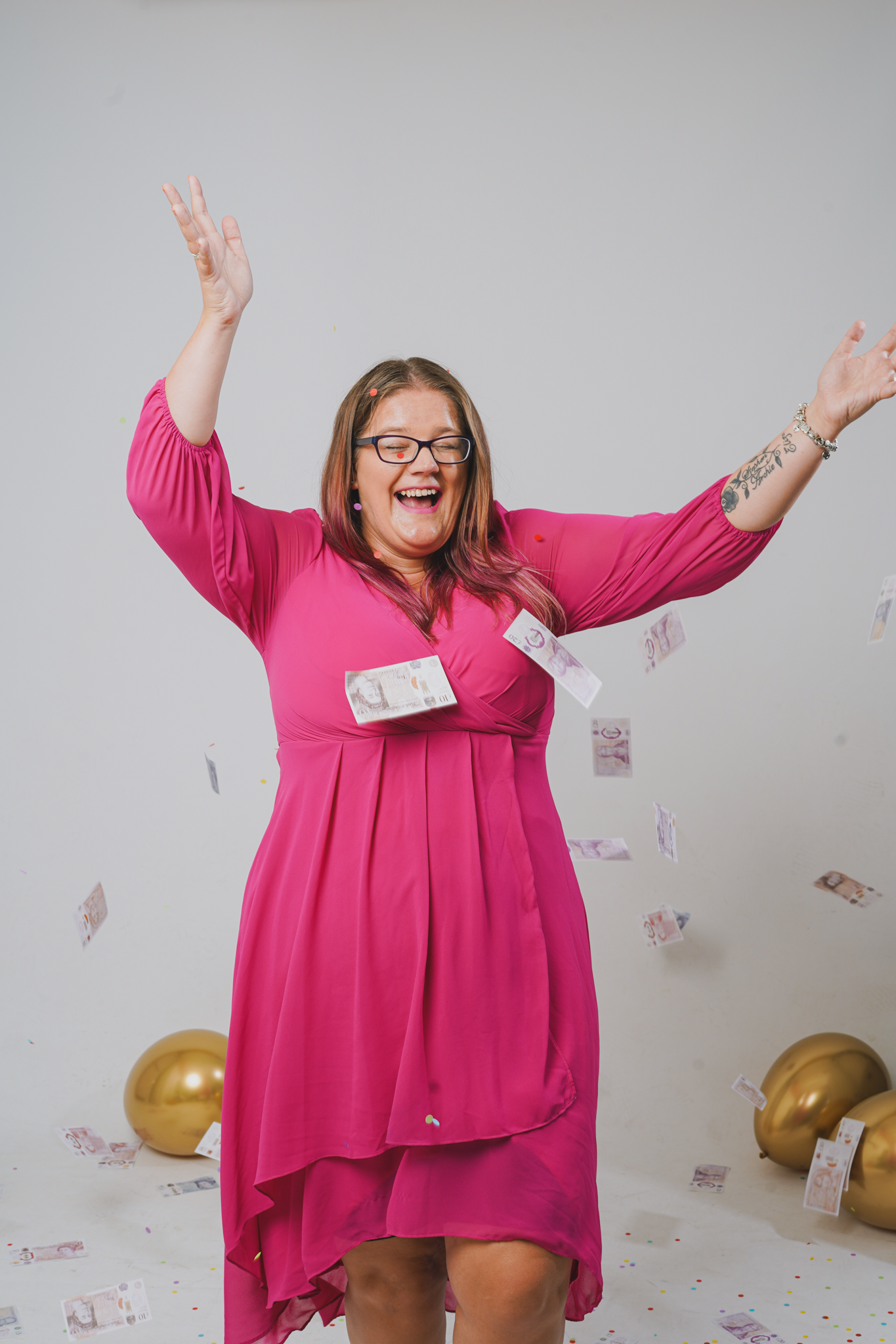 Dani in pink dress, laughing expression, surrounded by gold balloons and falling money.