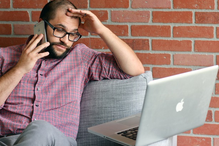 Frustrated Business Owner - Man on Phone looking at his laptop