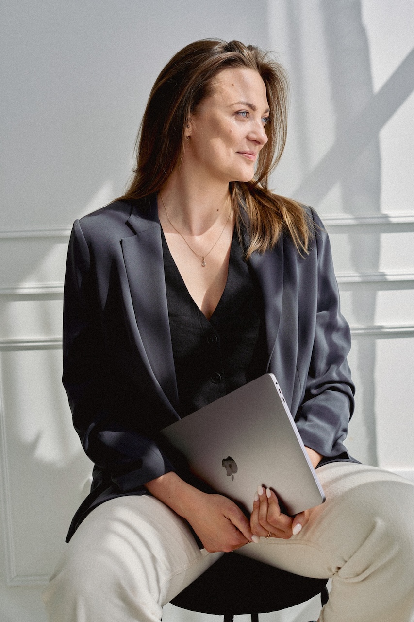 Eine Frau sitzt Lächelnd vor einem Laptop