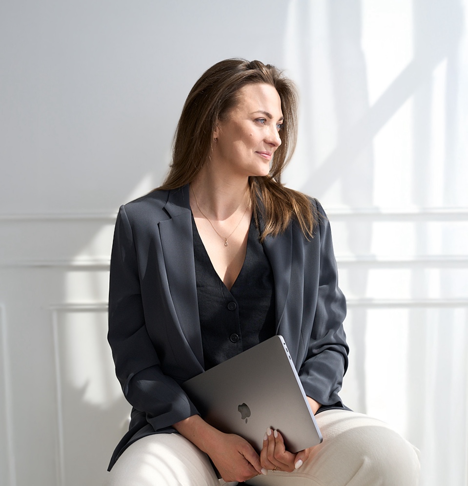 Eine Frau sitzt Lächelnd vor einem Laptop