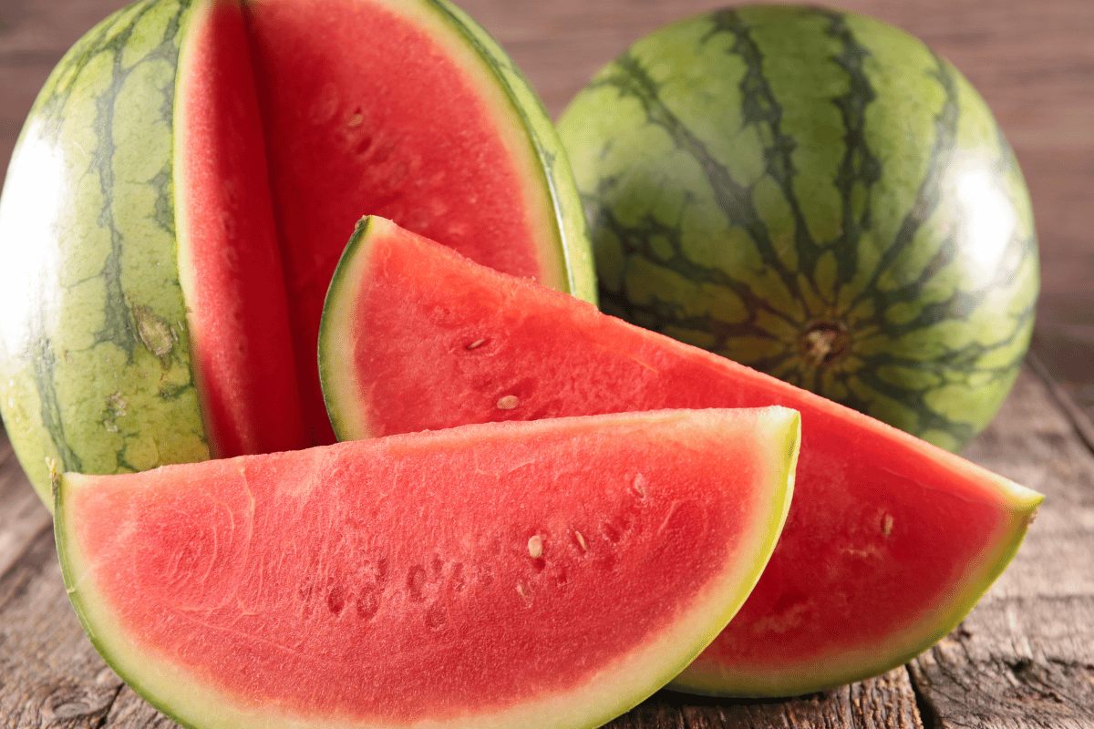 An image of water melons and slices of watermelon on a table