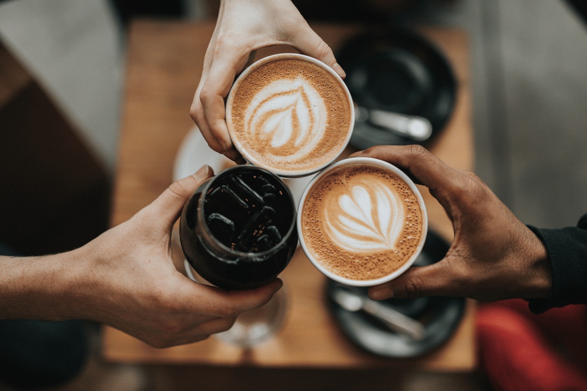 photo of three hands holding coffee mugs 