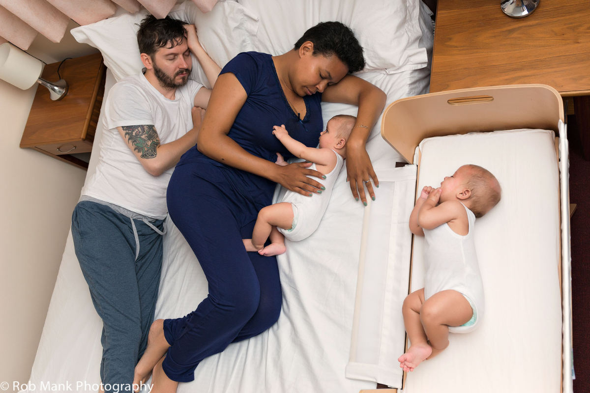 photo of mum and partner in bed with twins, one in bed and one in a co-sleeping cot