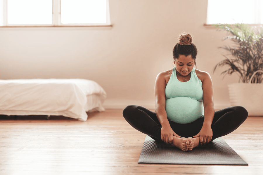 Image: pregnant person of colour holding bump with eyes closed