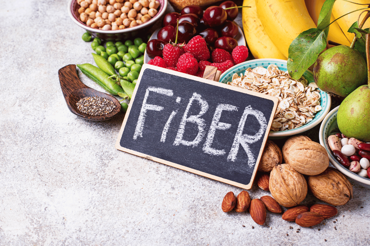 Photo of fiber rich foods, including fresh fruit, legumes, nuts and seeds and a fiber sign