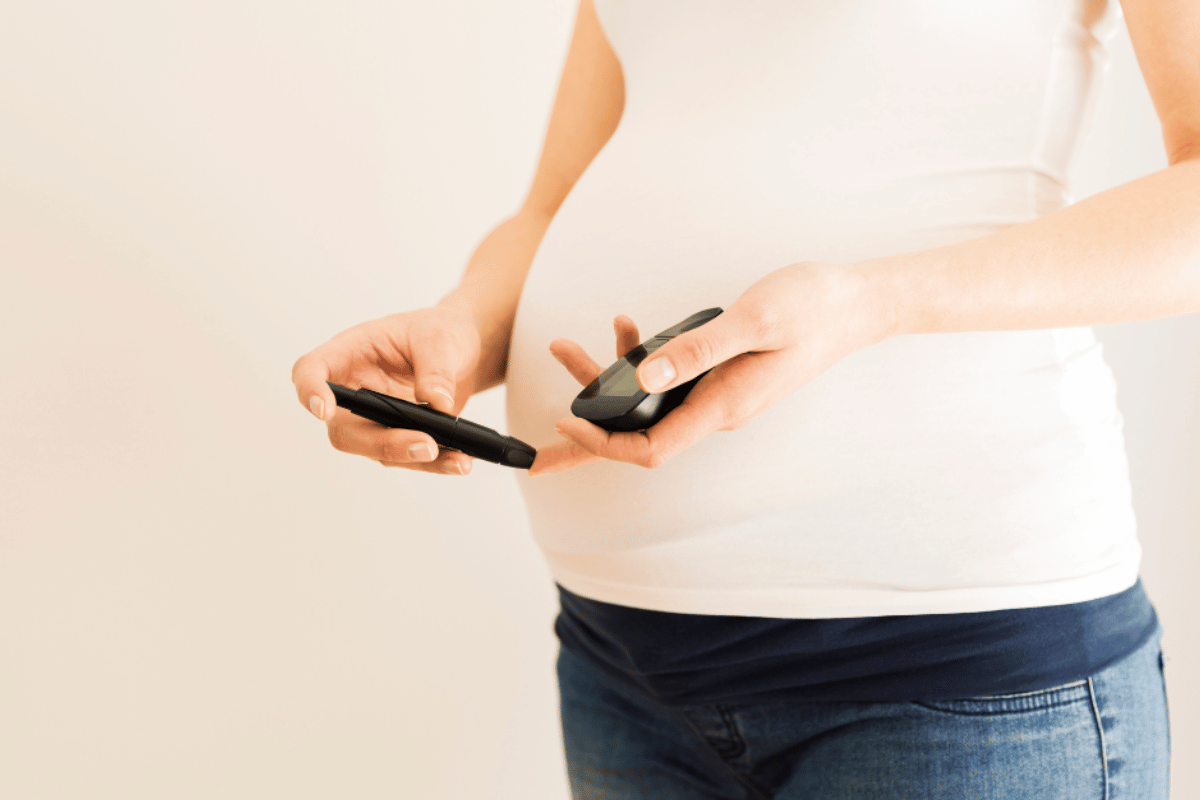 image of a pregnant woman testing her blood glucose levels.
