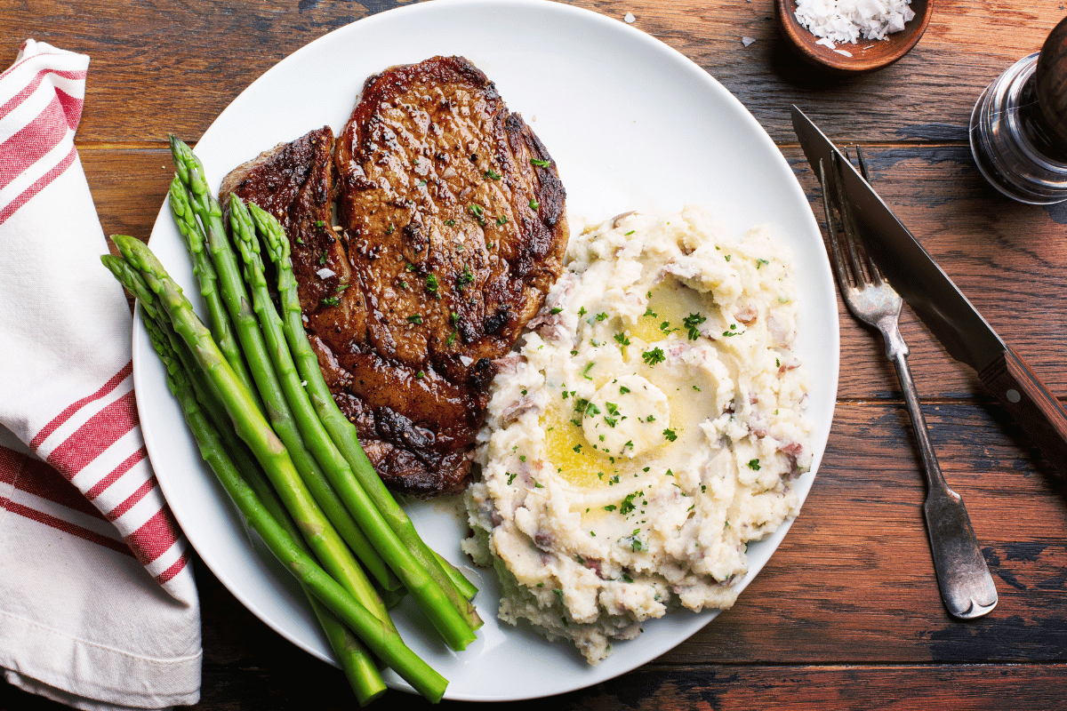 photo of steak, green beans and mashed potato plated on a table