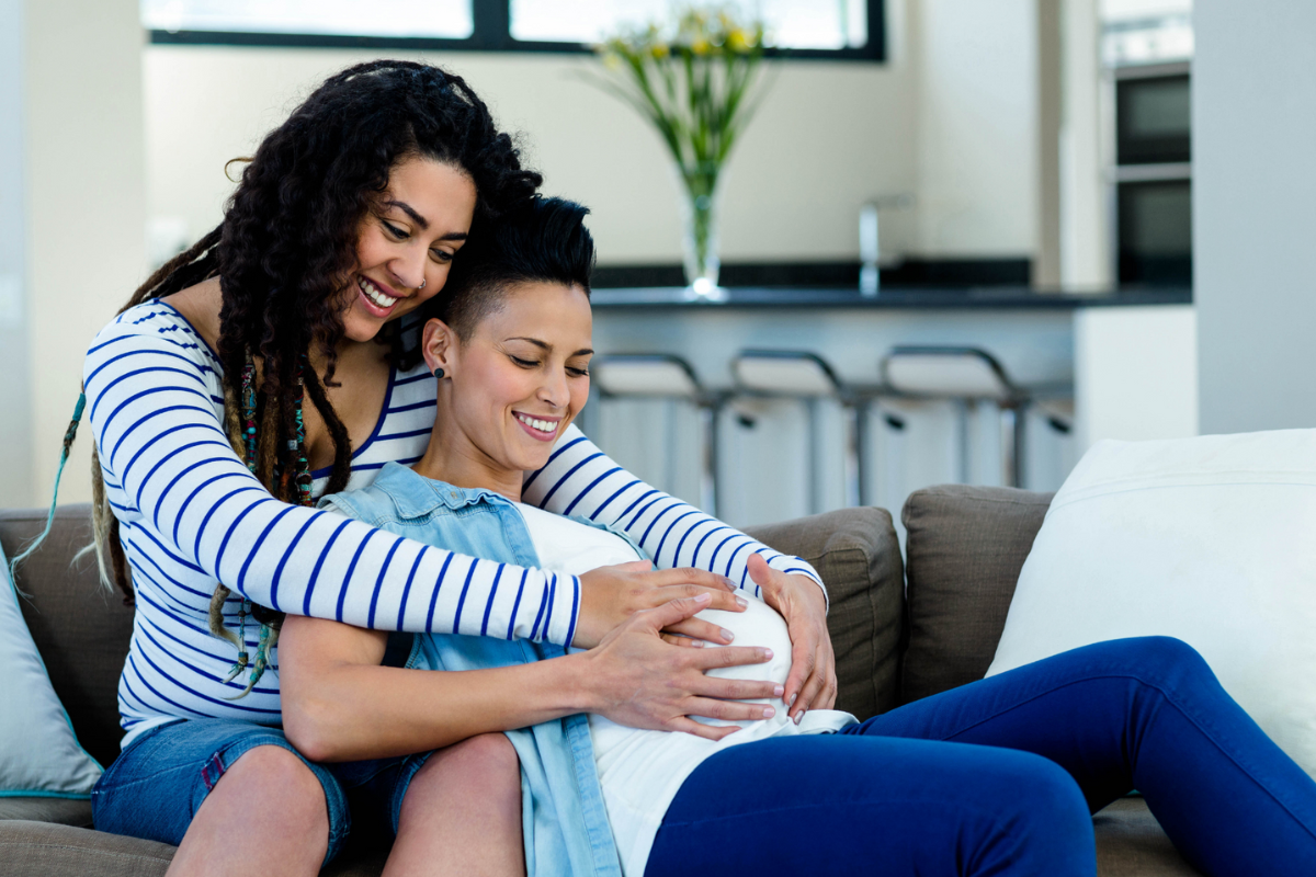 pregnant woman leaning back into her partner on a sofa
