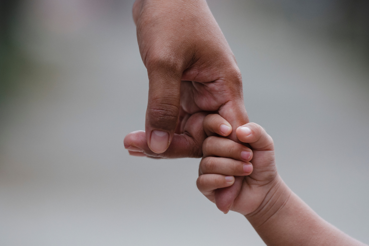 a photo of a parent holding an infants hand