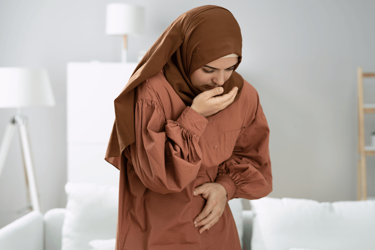 pregnant muslim woman indicating she feels nauseous