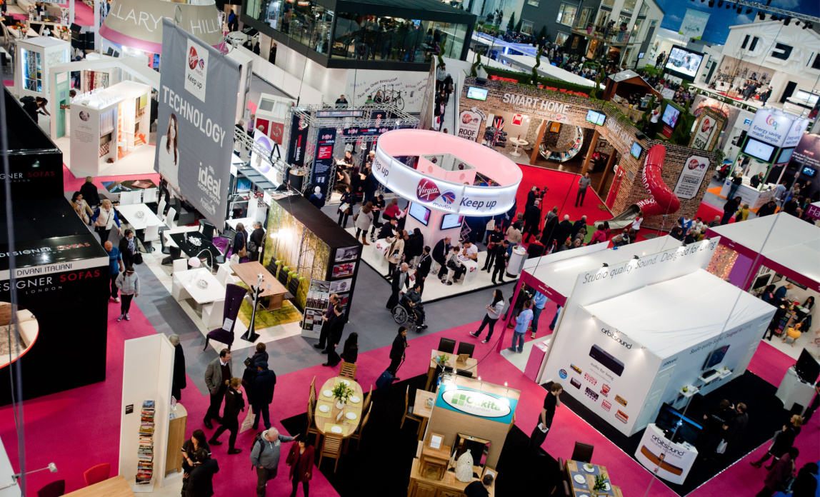An aerial view above an expo with various bright stands and people walking around