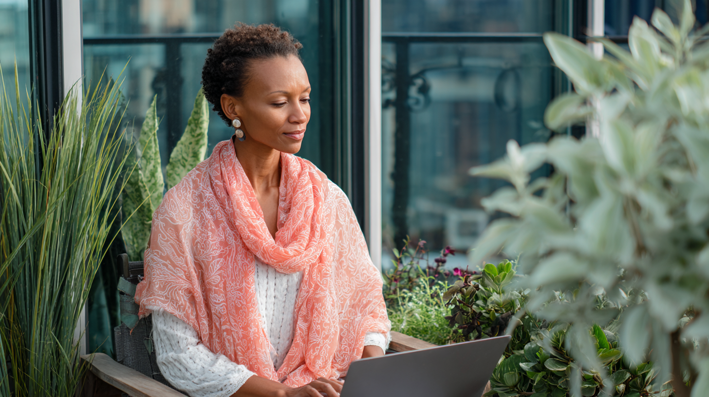 Photo of confident woman leader on the balcony in natural light, using her laptop