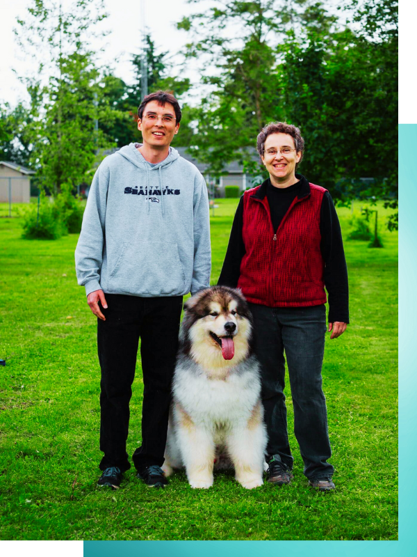 Peter and Lisa smiling, standing with dog outdoors