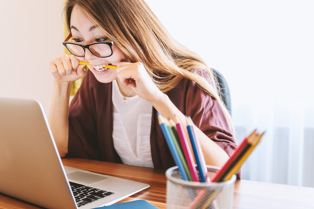 Excited student at computer biting pencil