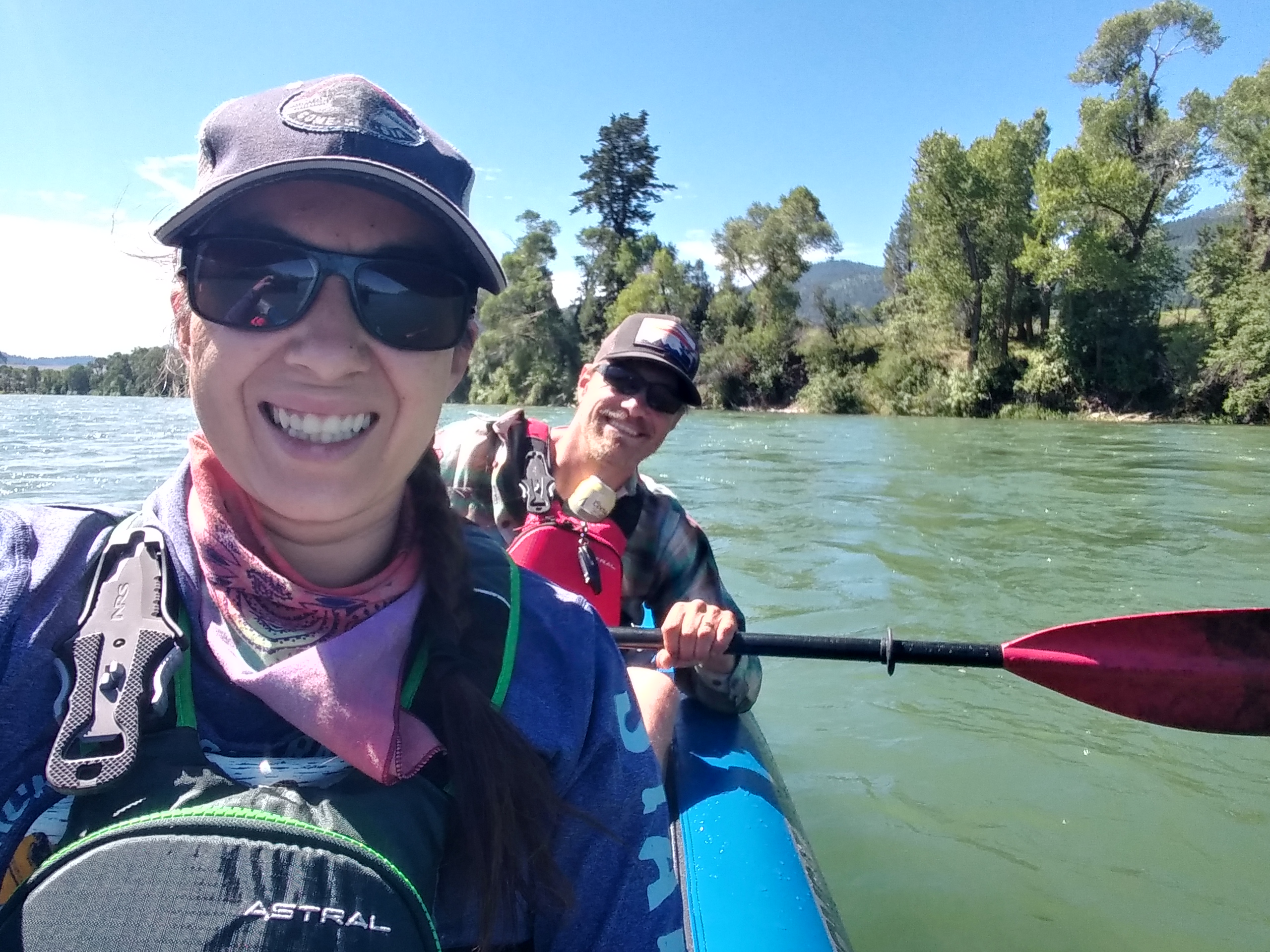 A smiling selfie of Rise Self-Protection owner Justina and her husband rafting down a lazy river on a sunny summer day.