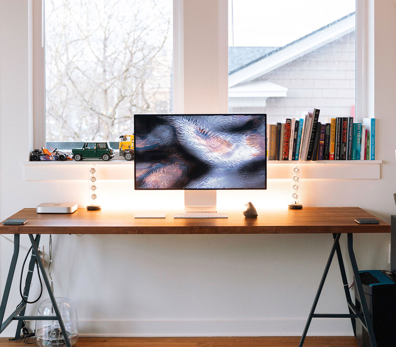 Image of a computer monitor on top of a desk in front of a window