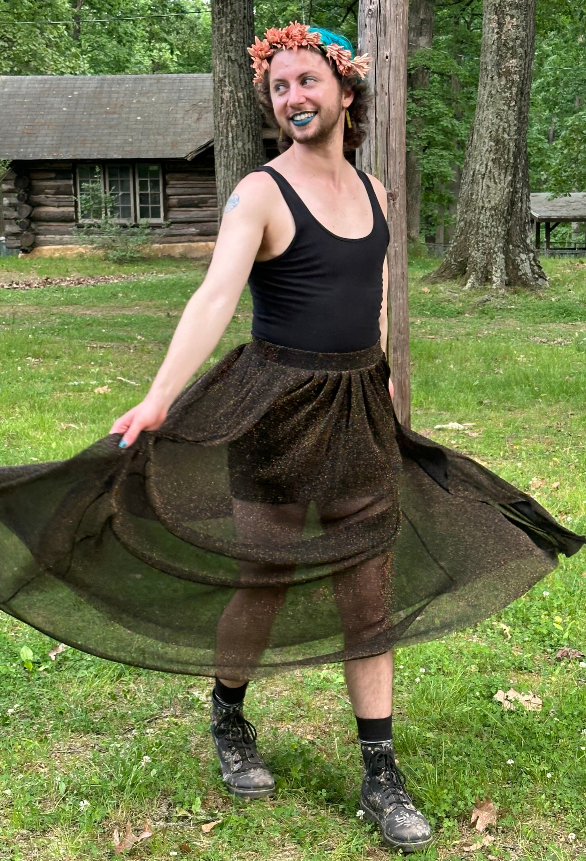 Photo of River wearing a black dress with gold sparkles, a flower crown, and black boots