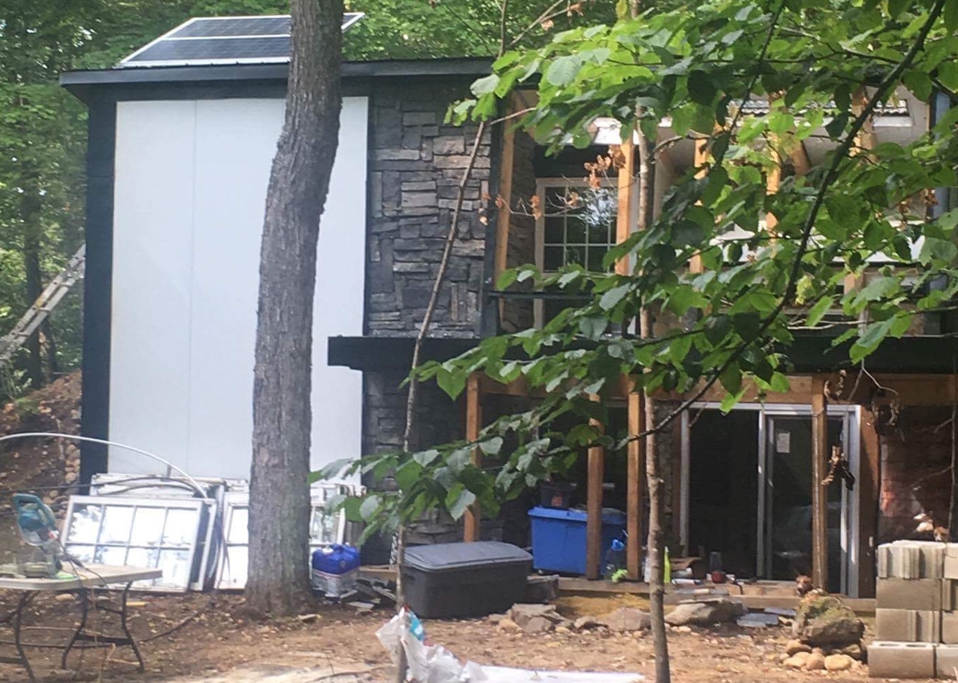 Prototype house in forest with solar panels and sustainable materials from an off-grid housing initiative.