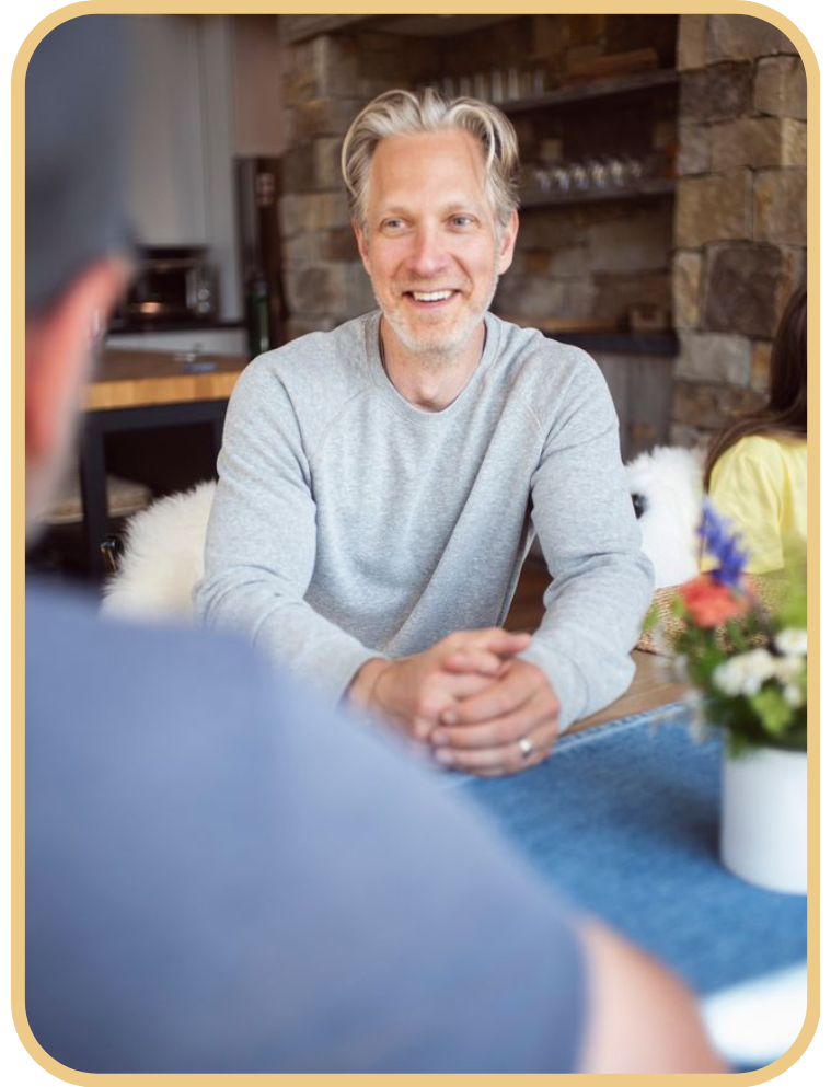 Person smiling warmly during a relaxed coaching conversation at a table”