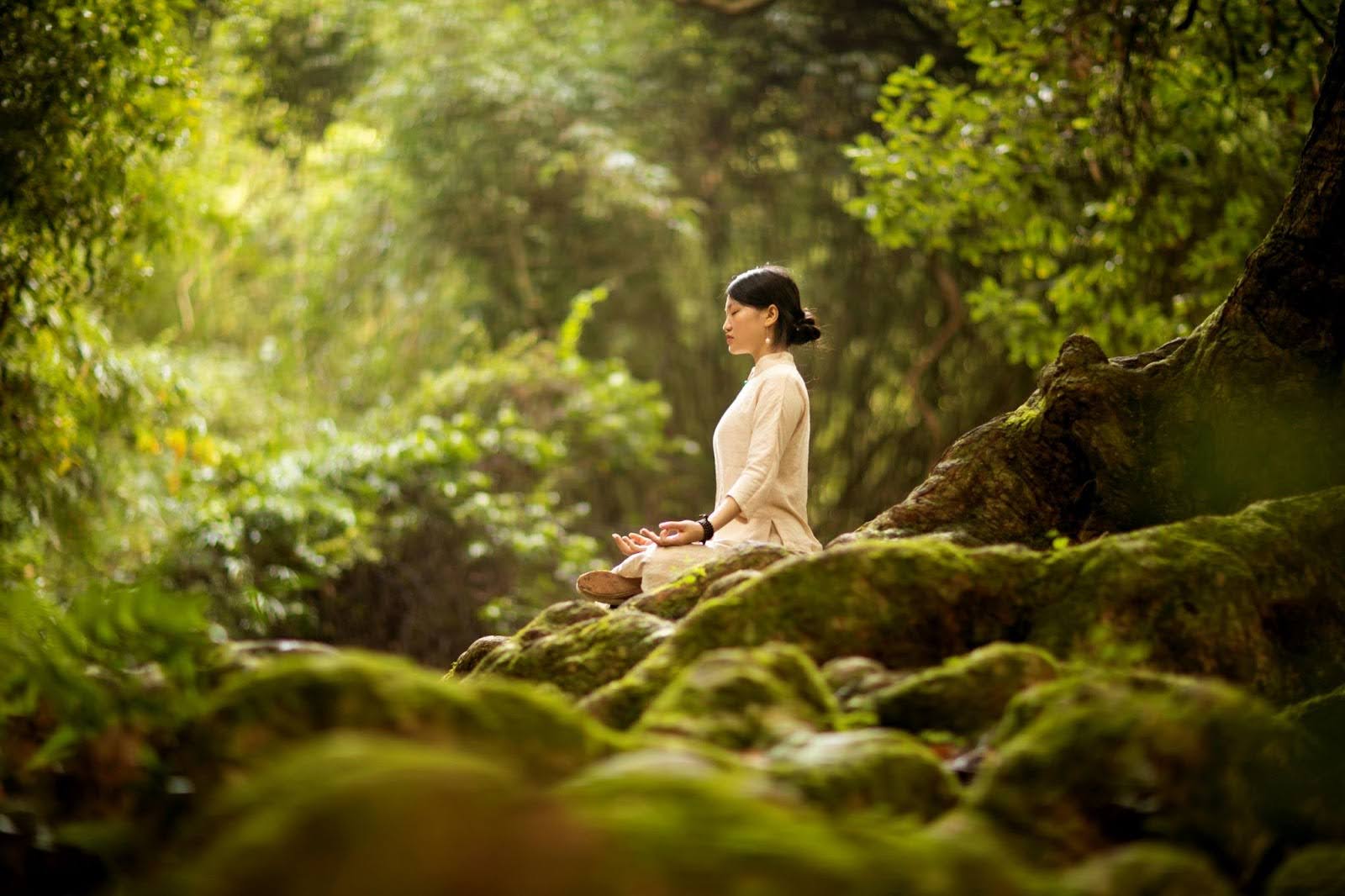 Woman meditates in nature, symbolizing mindfulness and self-reflection